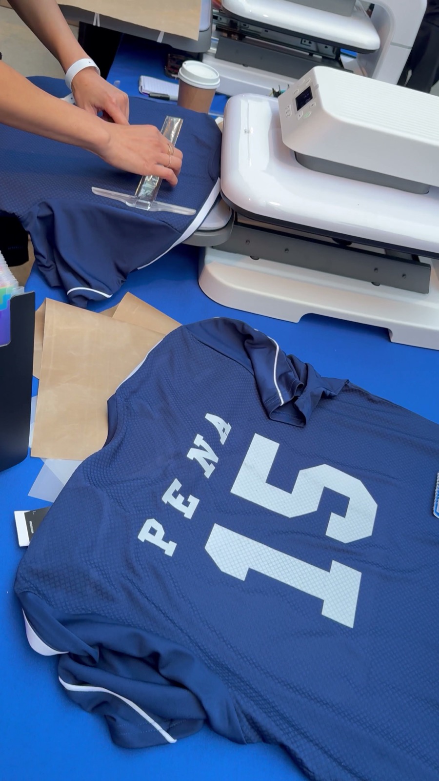 Crew member pressing a full-color DTF transfer onto a custom navy jersey at a live event station