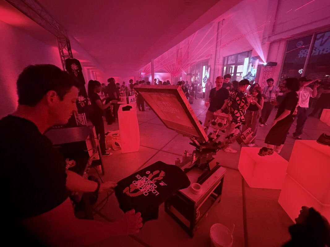 Live printing station drawing a crowd at a red-lit nighttime brand event