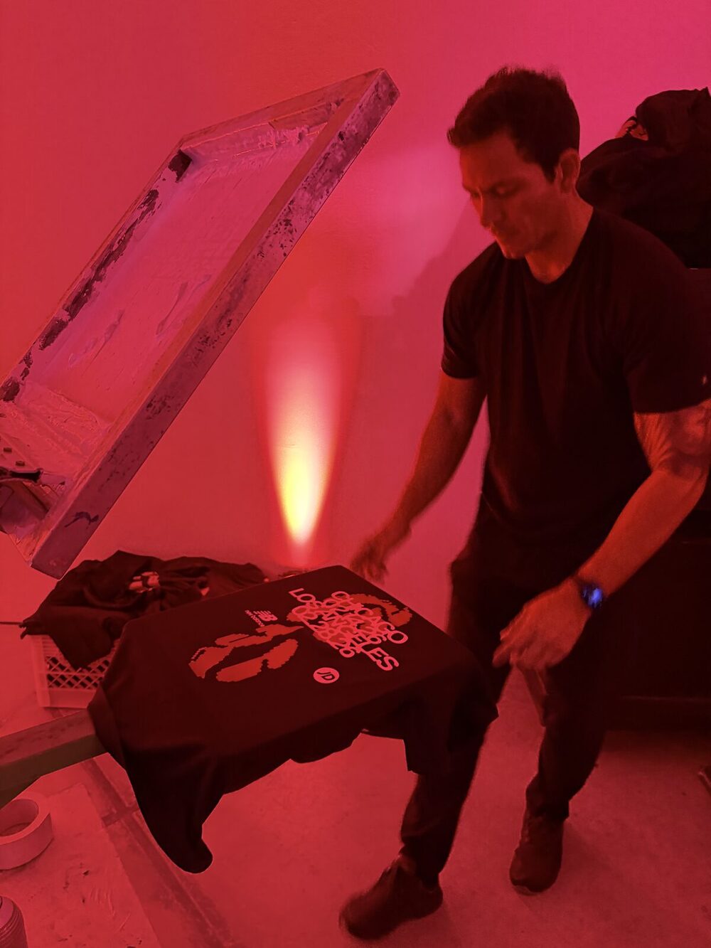 Freshly pressed shirt with detailed artwork resting on the press platen under red event lighting